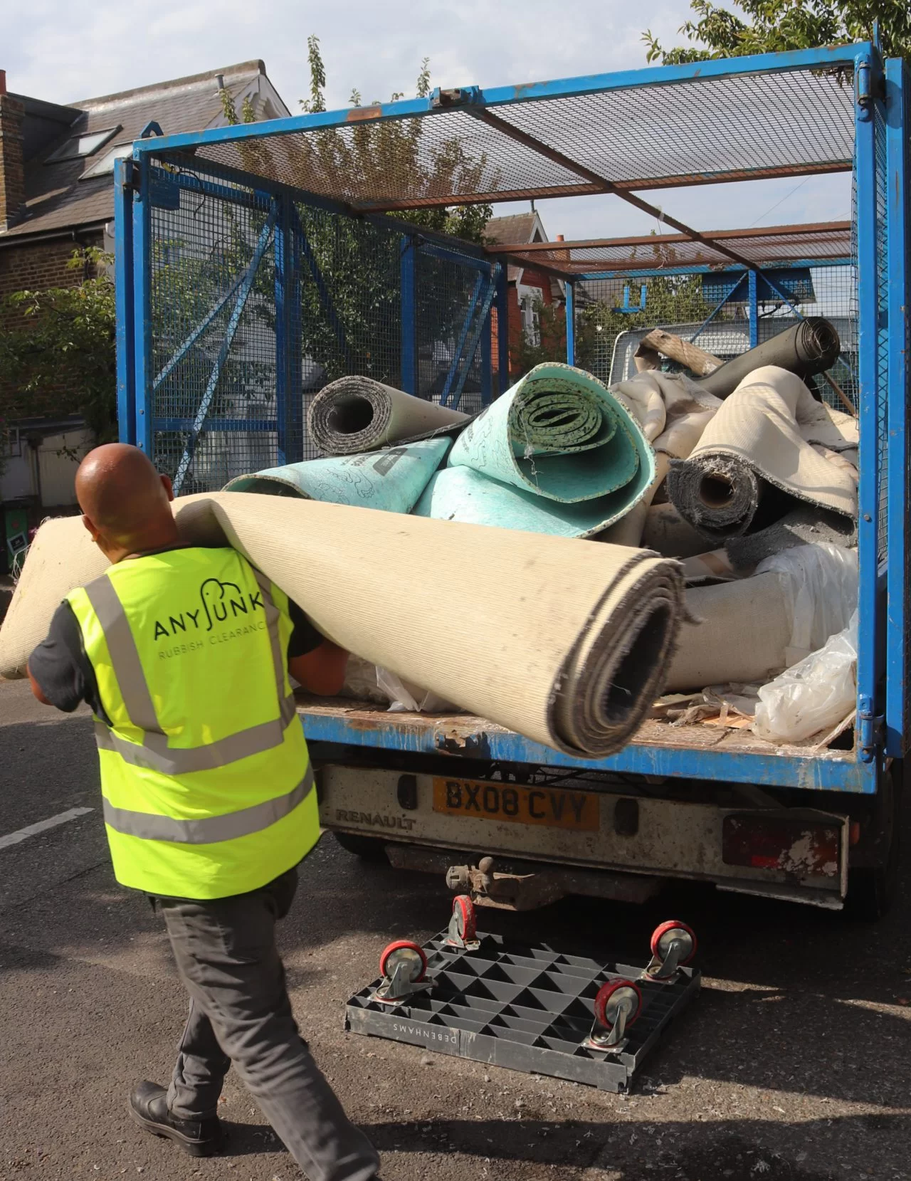 any junk man and van waste contractor carrying rolled carpet into truck for disposal