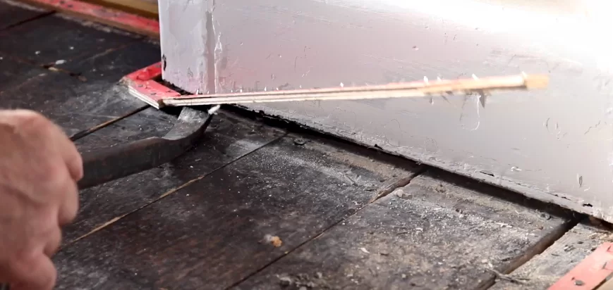 man using crowbar to uplift red gripper roads from floor
