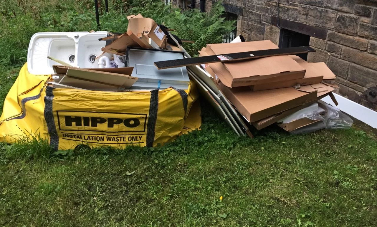 yellow hippobag overfilled with bathroom waste and carboard lying next to bag